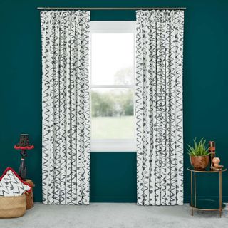 Abigail Ahern Wolfe Smoulder Curtains set against dark teal walls in living room with side table