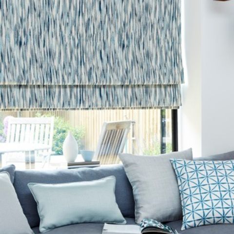 A large window fitted with a Roman blind in Impression Marine with a blue couch in front of it