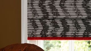 Sofa next to window covered by Cadillac Noir Roman blinds with Colette Vixen fringing