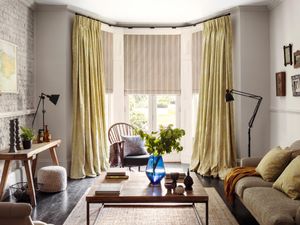 A living room with Oralia Ochre Curtains and Howard Natural Roman blinds