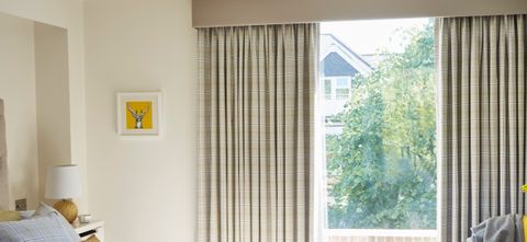 A bedroom with Wallace Chartreuse curtains fitted to the window
