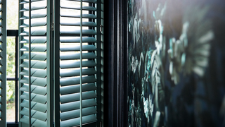Closeup of green custom colour shutters in a bedroom
