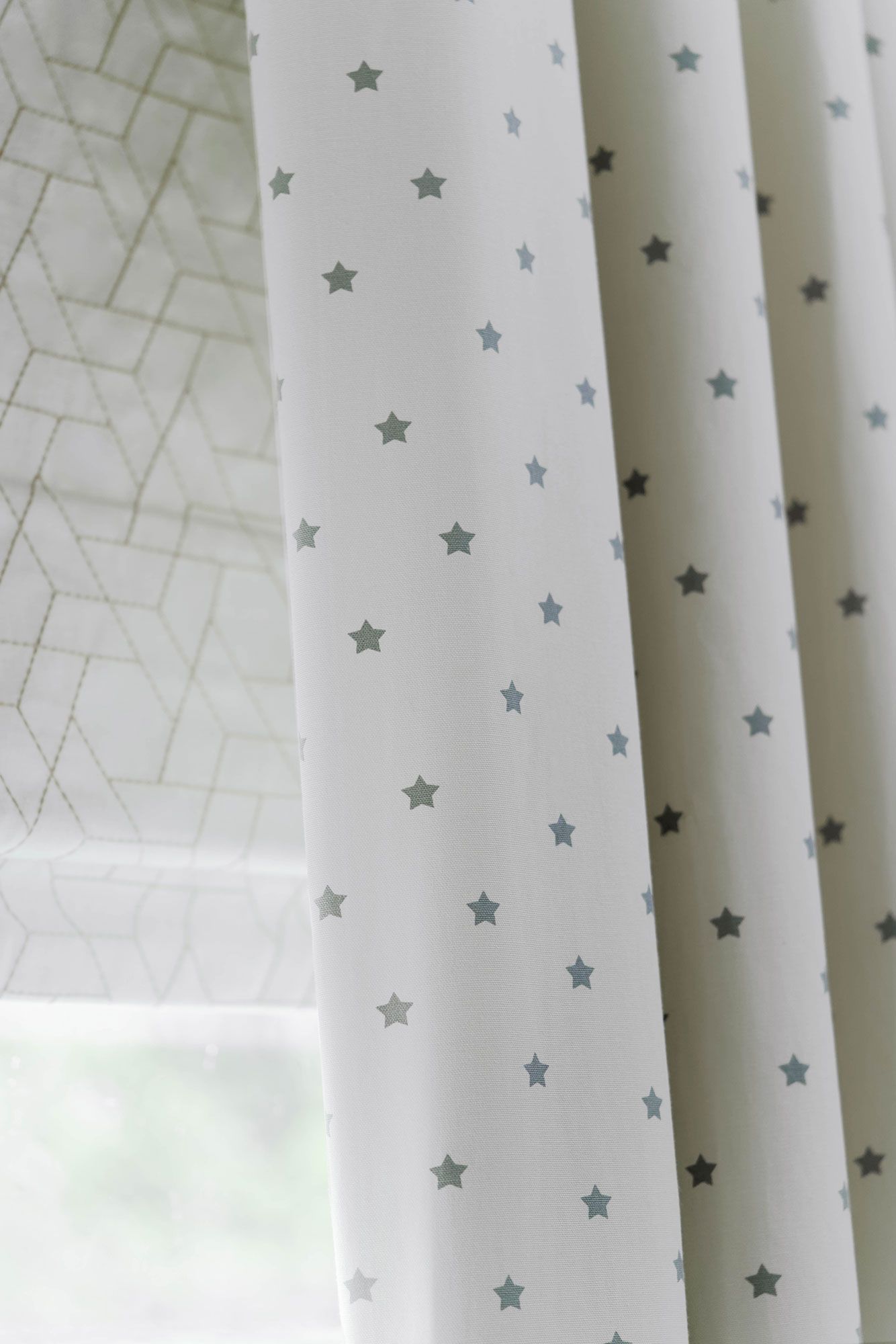 Close up of Polaris Ivory curtains and Jive Mallow romans in children bedroom