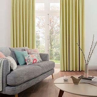 Furnished living room with Lotta Citron curtains over a glass door