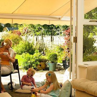 A yellow awning shades a family sitting outside on a sunny day