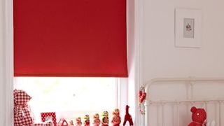 Bright red Acacia Pillerbox roller blind hung in bedroom