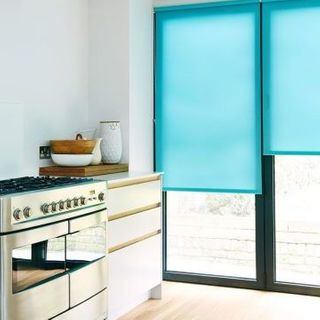 Plain blue Ravenna Aqua roller blind hung in kitchen