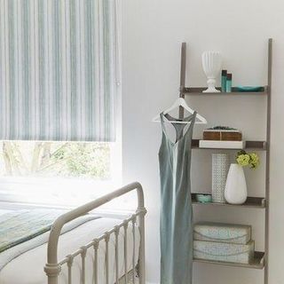 Roller blinds in striped Melia Mineral, hung in a stylish urban bedroom