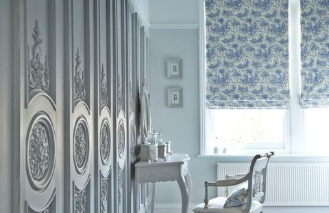 Large white room with ornate wooden panels on the walls and two Roman blinds fitted to the windows in Toile French Blue fabric