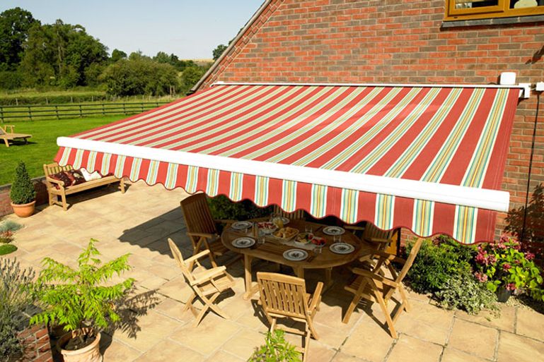 A red striped awning hanging over patio furniture