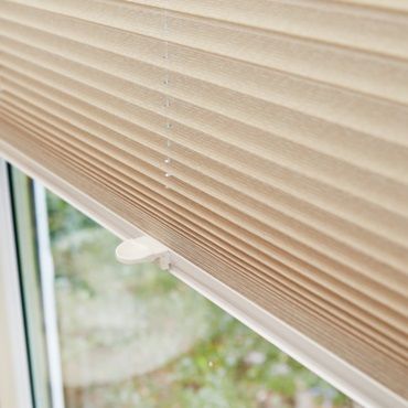 cream pleated blinds in a window close up