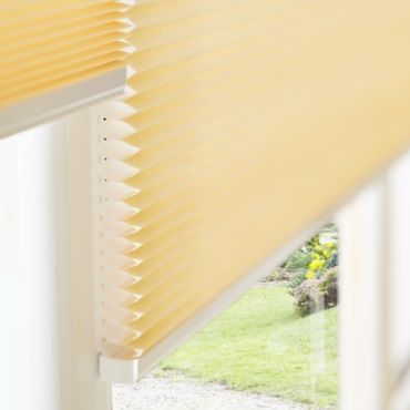close up of yellow pleated blinds fitted in a window