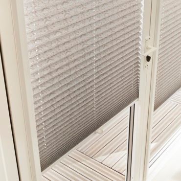 close up of grey pleated blinds in a patio door