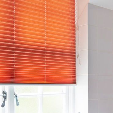 close up of orange pleated blinds