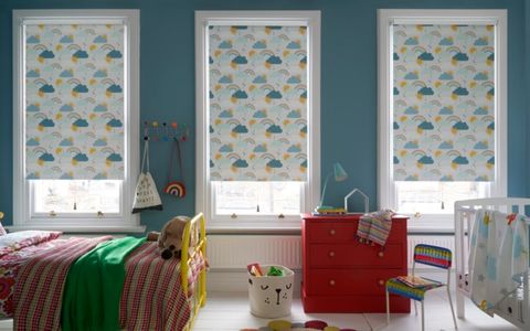 A child's bedroom with 3 windows, each fitted with a Roller blind in Rainbow Dreams Multi Colour fabric