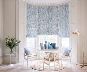 Traditional dining area in a bay window enclave dressed with blue floral roman blinds