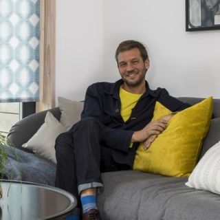 Charlie Luxton sat on a gray couch with yellow cushions