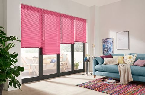 A white room featuring bi-fold doors that have individual bright pink Venetian blinds 