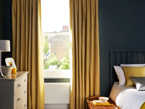 A bedroom with a sash window fitted with Curtains in Eclipse Mimosa fabric