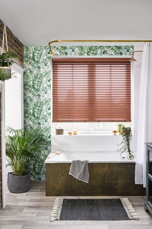 Nutmeg Faux Wood blinds hung in a leafy bathroom