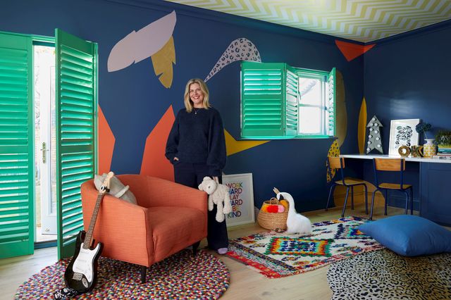 Erica Davies standing in front of custom colour shutters in bright green, fitted in a playroom