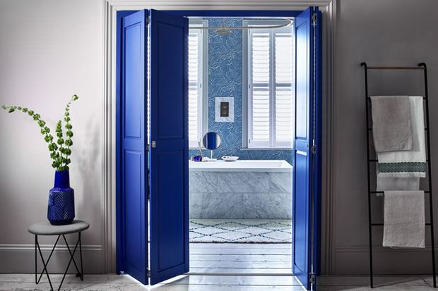 Solid tracked shutters in custom colour blue leading to bathroom