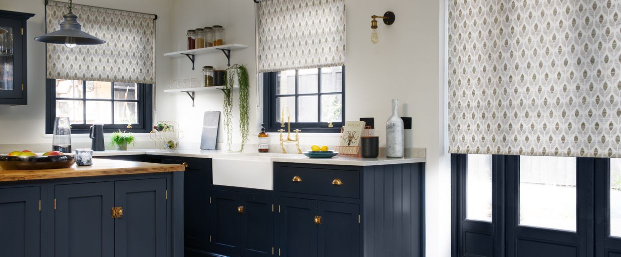 patterned grey roller blinds in a kitchen with deep blue units