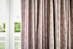 close up of neutral beige featuring delicate embroidery curtains and textured shimmering purple curtains hanging on doors