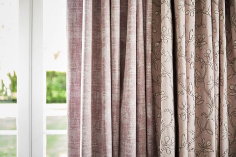 close up of neutral beige featuring delicate embroidery curtains and  textured shimmering purple curtains hanging on doors