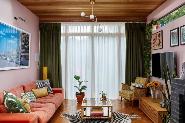 A pink, 70s style living room with wood panelled ceiling and floor
