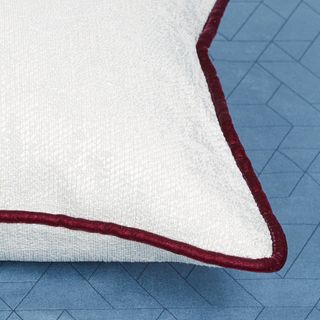 White cushion with a purple lining placed on top of a blue coloured fabric with a geometric pattern