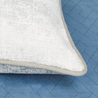 White and glistening decorated cushion with a beige coloured edge piping
