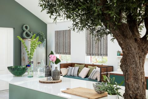 kitchen with a tree in the middle and grey roman blinds at the window