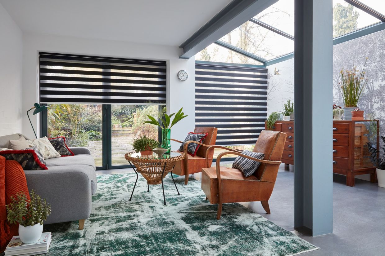 A room shot of an extension featuring a wide window covered by a black Dawn Day & Night roller blind.