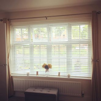 white wooden blinds and gold curtains hanging on windows in living room