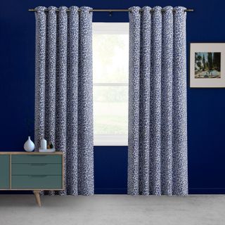 Partially closed Wild Cobalt curtain against a dark blue wall