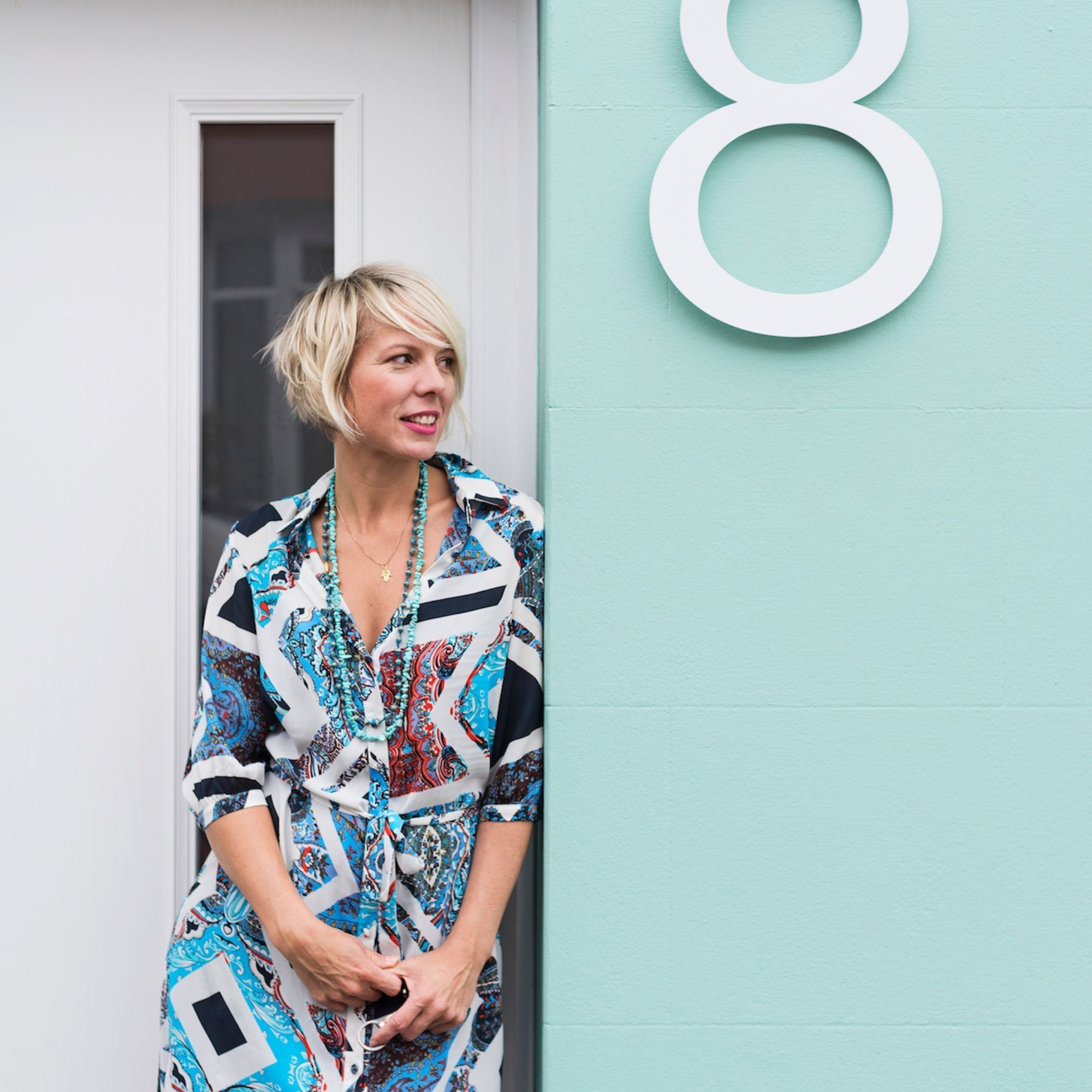 Maxine Brady leaning against a blue wall that has a number eight on it