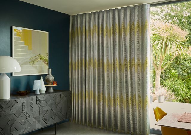 Zaha Sunrise Curtains fitted to a tall door window in a dining room with blue coloured walls