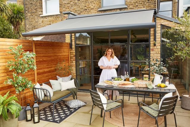 Sally Cullen standing on the patio in her garden with an awning covering the patio