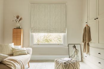 cream coloured roman blind with a white vertical pattern fitted to a window in a white decorated living room