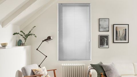 Silver coloured venetian blinds fitted to a tall window in a living room