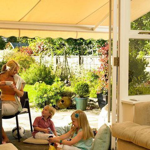 A yellow awning shades a family sitting outside on a sunny day