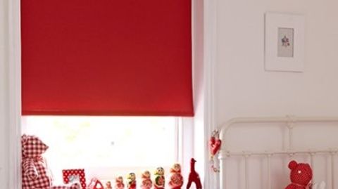 Bright red Acacia Pillerbox roller blind hung in bedroom