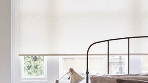 Plain Norfolk Ivory roller blind hung in bedroom