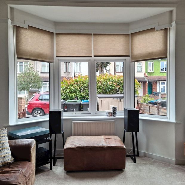 Jerico natural brown roller blinds in bay window in living room