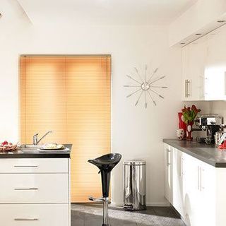 Light wood Portfolio Ivory Venetian blinds hung in a modern kitchen