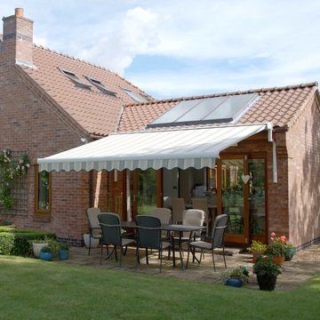 A grey awning shading patio furniture in a garden