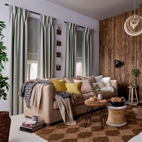 Rustic, cosy Living Room with two windows dressed with Lindora Silver Curtains and Howard Chartreuse Roman Blinds behind a sofa with cushions and blankets