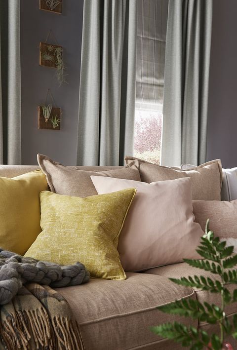 Cosy Living Room Sofa with Cushions and Blankets in front of a window dressed with Grey Curtains