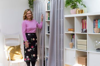 Liz Earle stood in front of a bookshelf with voile curtains fitted to it
